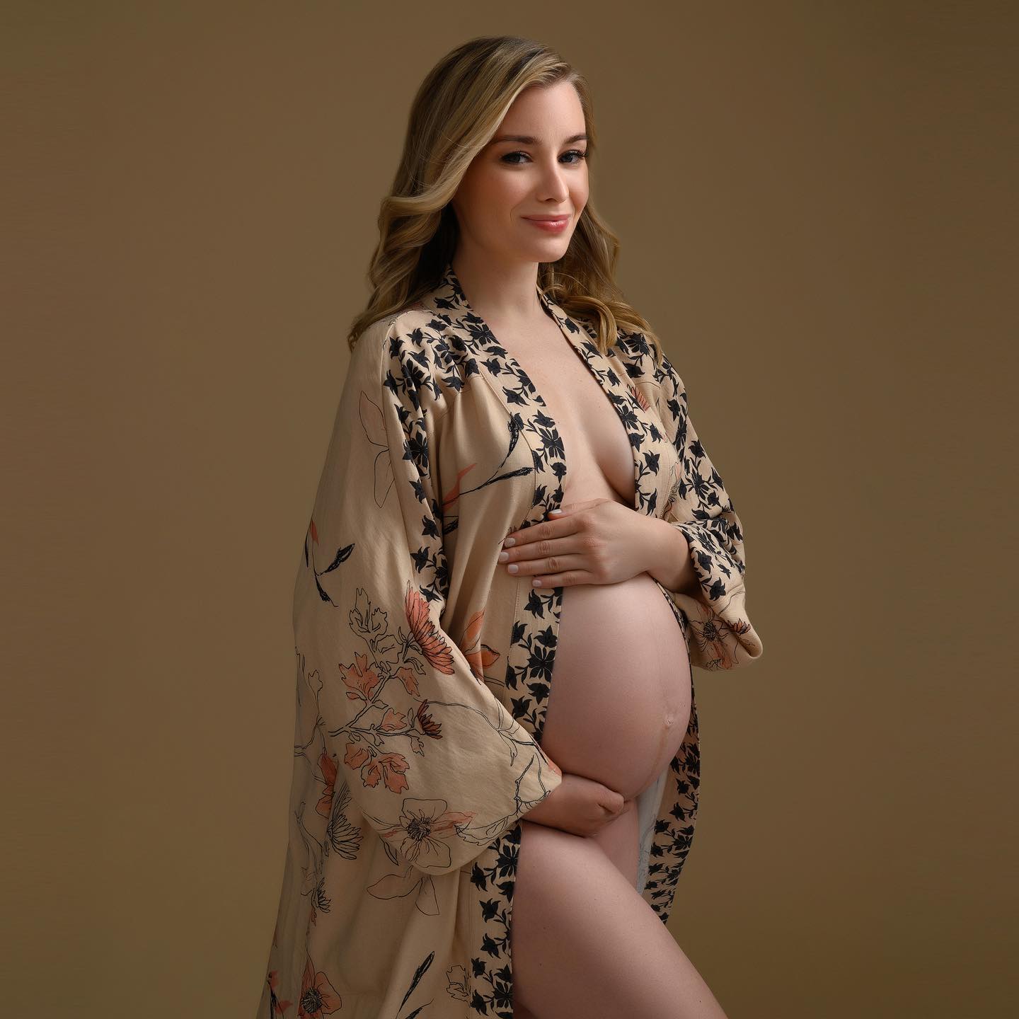 Pregnant woman weating a kimono posing in brown background. 