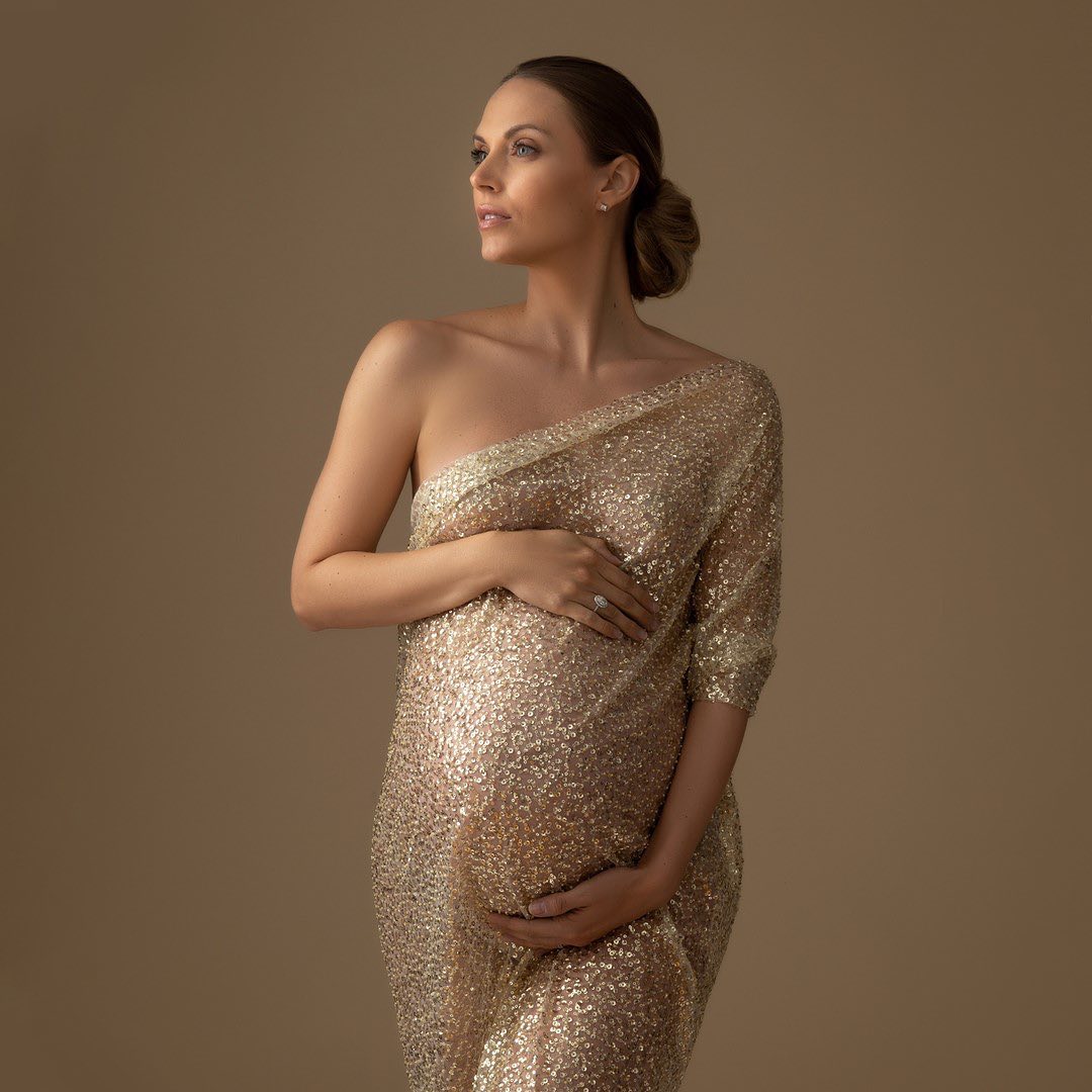 Pregnant woman posing in beige background. 