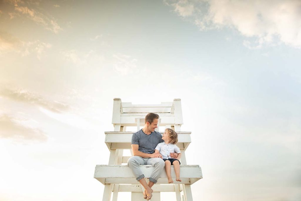Father and his young son sitting on a lifeguard tower at a beach near Greenwich, CT.
