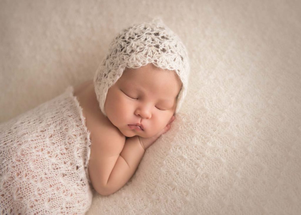 Sleeping baby in a knit blanket and a beautiful bonnet