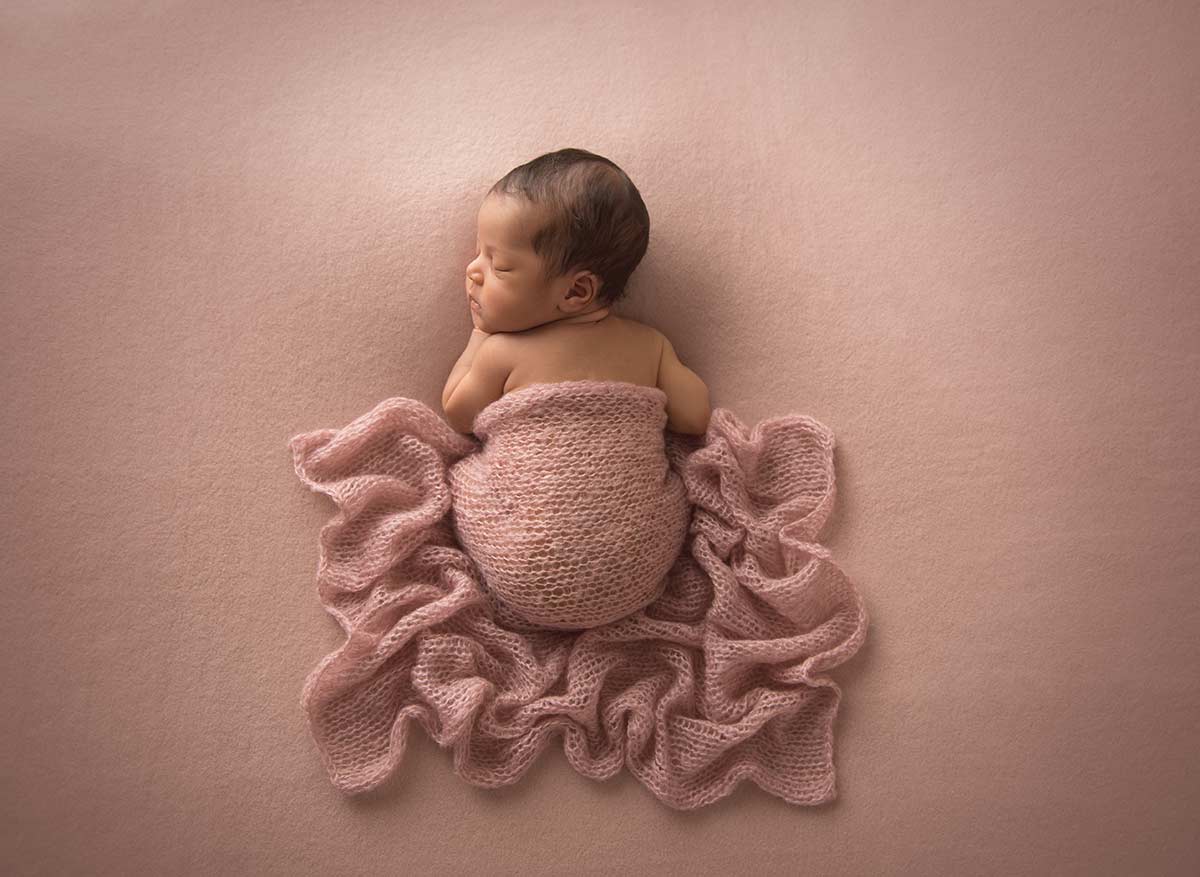 Infant girl sleeping in a knit cover in this beautiful newborn photograph taken in Denver Colorado.