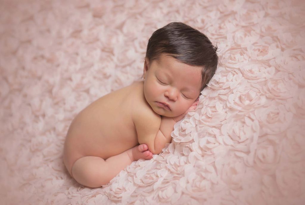 Bed of roses with a sleeping baby as captured by a newborn photographer.