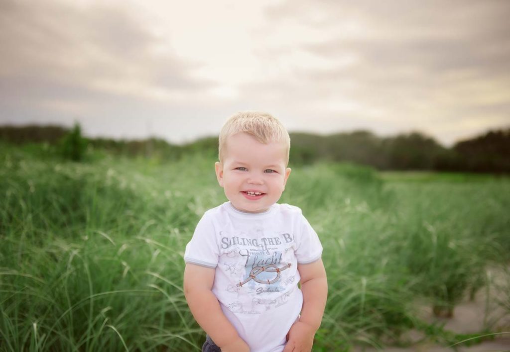Happy boy standing in beach sand dunes in Connecticut