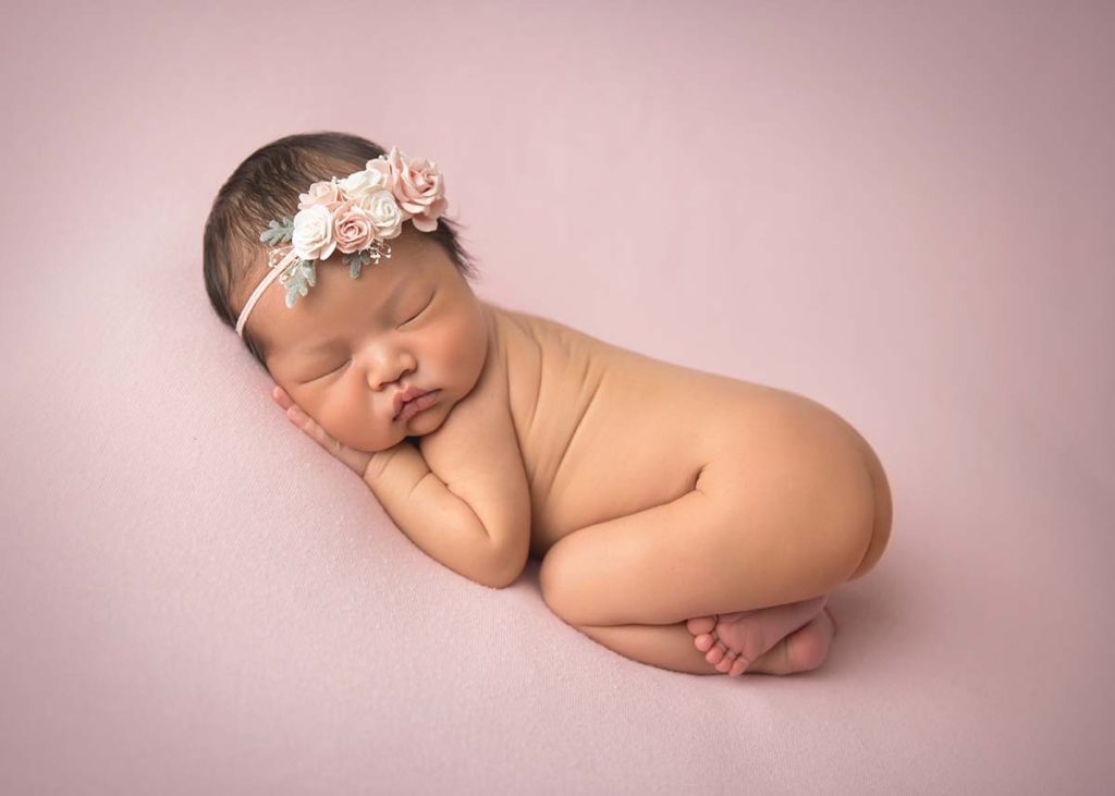 Stunning newborn photo of a sleeping baby wearing a headband in Armonk NY.