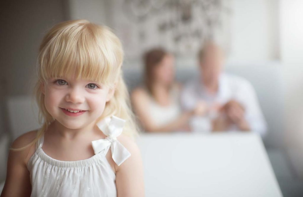 blonde girl sitting kitchen table Blonde girl with parents in the background