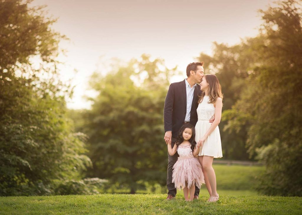 A family from Bronxville, NY posing for a family photograph in a park setting during sunset.
