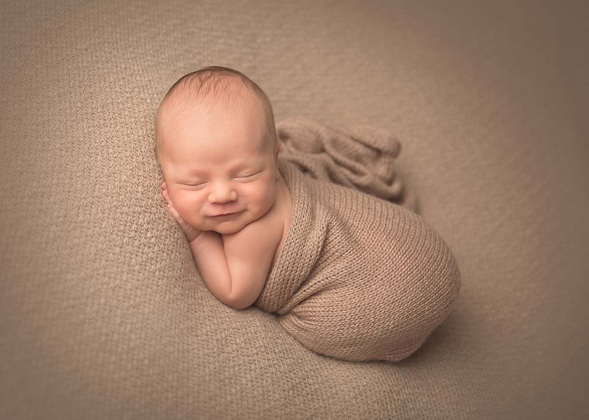 Brown blanket wraps around a sleeping newborn in this photo taken at a photography studio in Denver, CO.