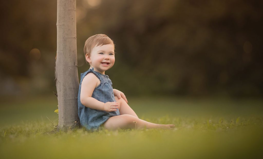 child sitting against tree Adorable baby girl sitting near a tree in a Westchester county park