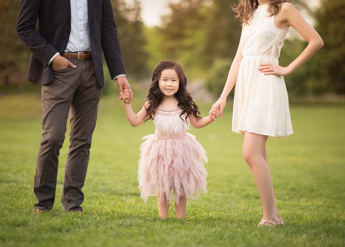 Mother and father holding their daughter's hands in this lifestyle family photo taken on a farm in Colorado
