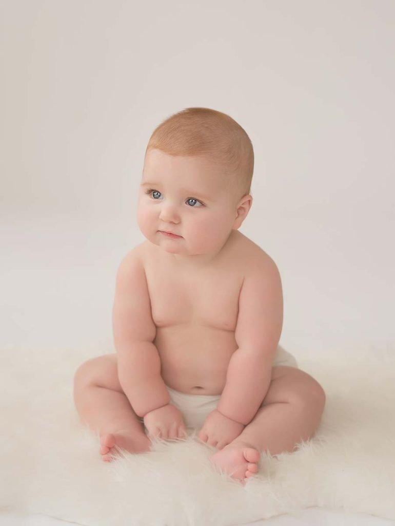 Cute chubby baby boy sitting in a photo studio