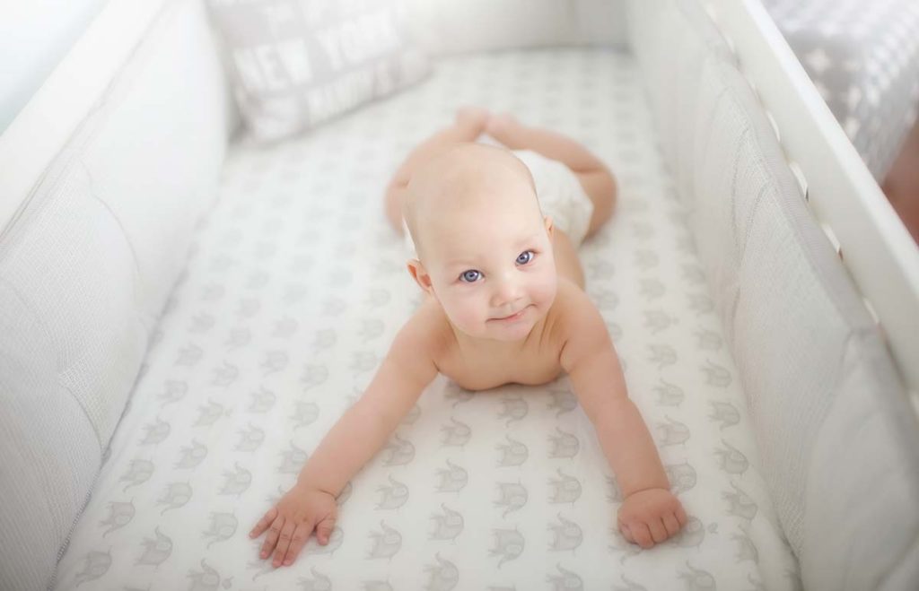 crib elephant bedding baby Baby with blue eyes laying in his crib