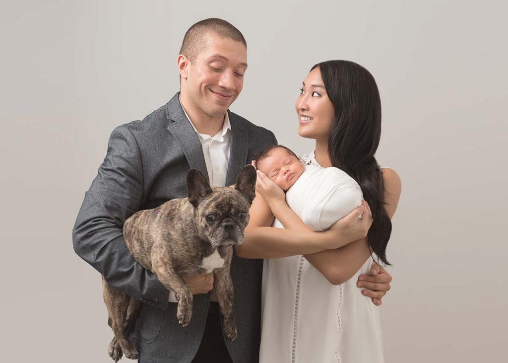 A candid moment shared amongst parents along with their infant baby and family pet in this beautiful photo captured by a newborn photographer in Scarsdale, NY.