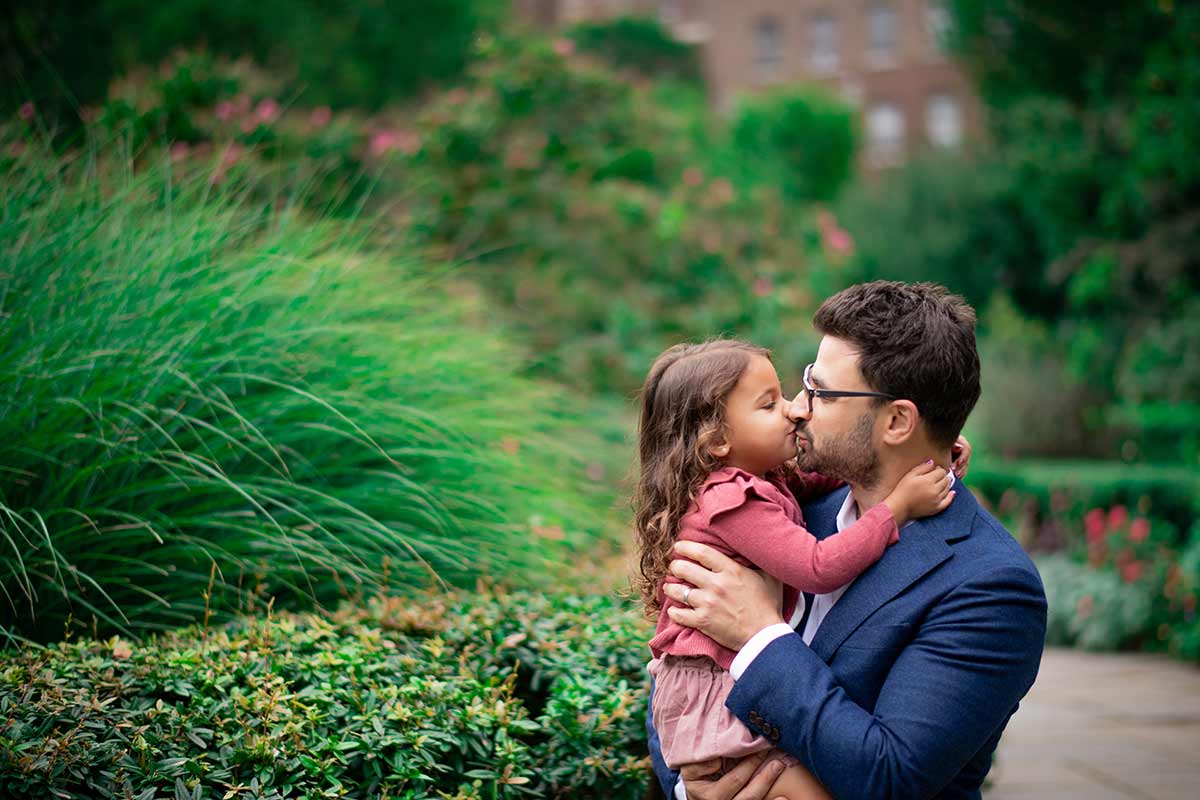 Dad kissing his baby daughter in botanical gardens in Connecticut