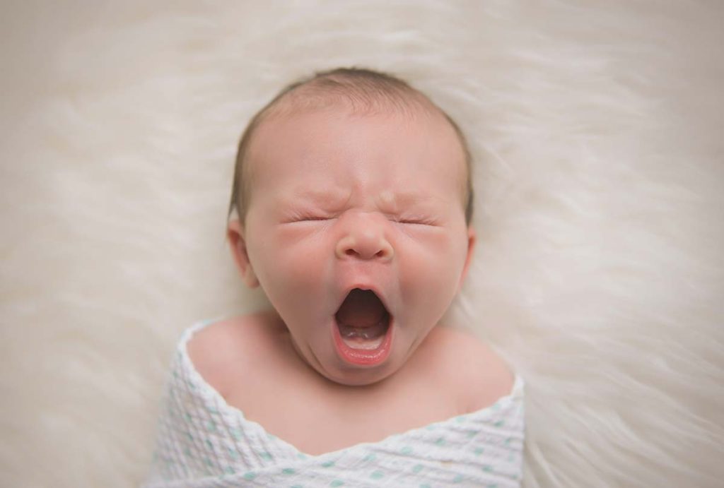 Newborn baby yawning in this refreshing newborn photo