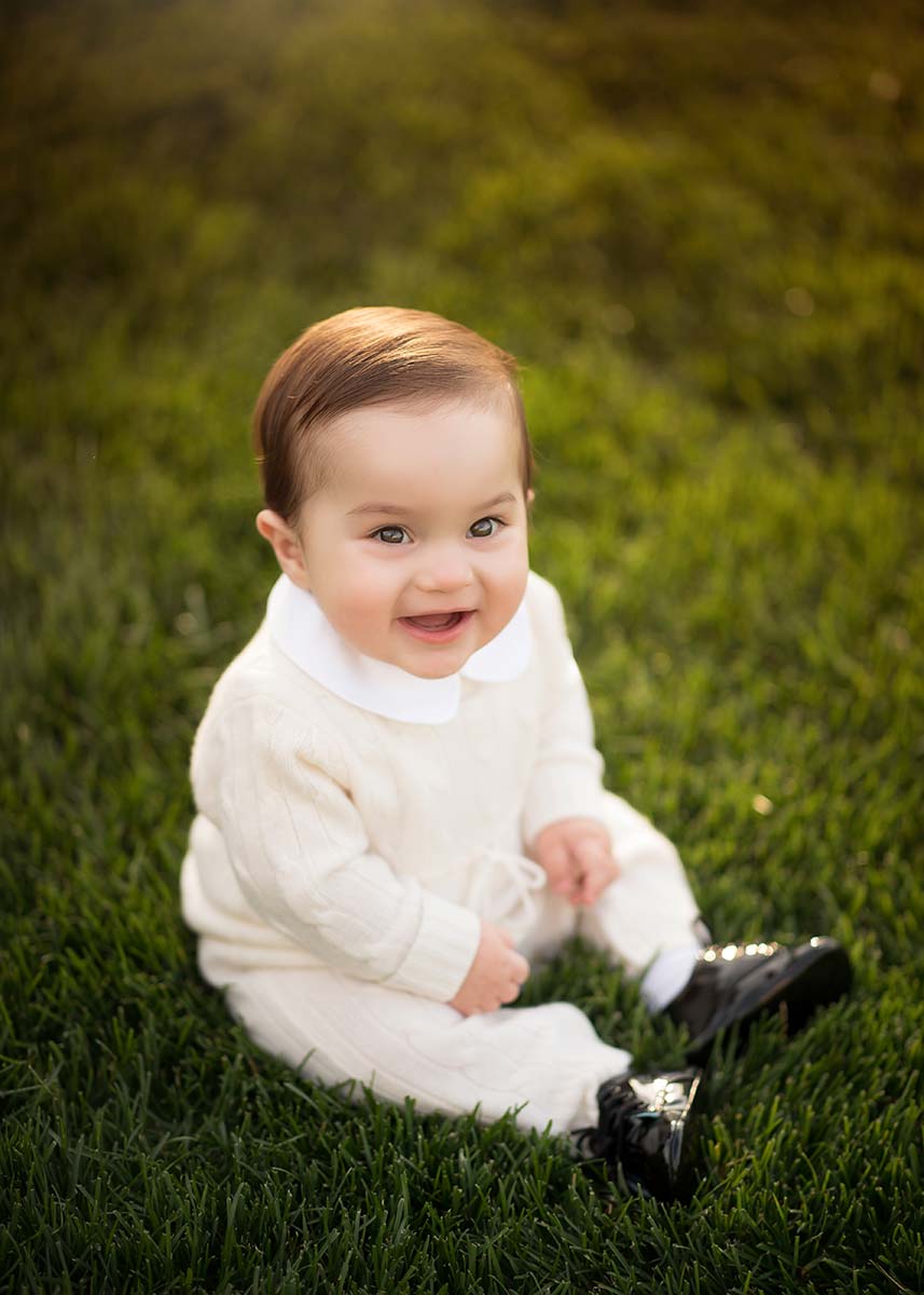 Little boy in a formal outfit laughs at a baby photographer