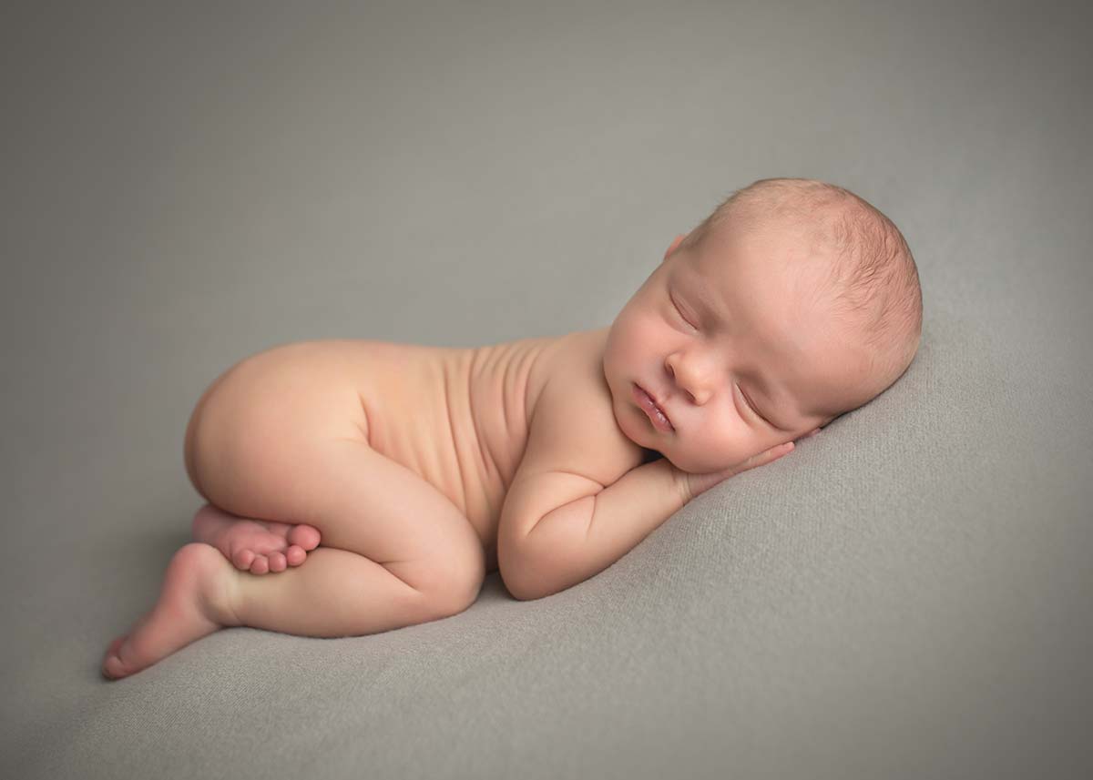 Classic newborn portrait of a sleeping baby on a gray blanket