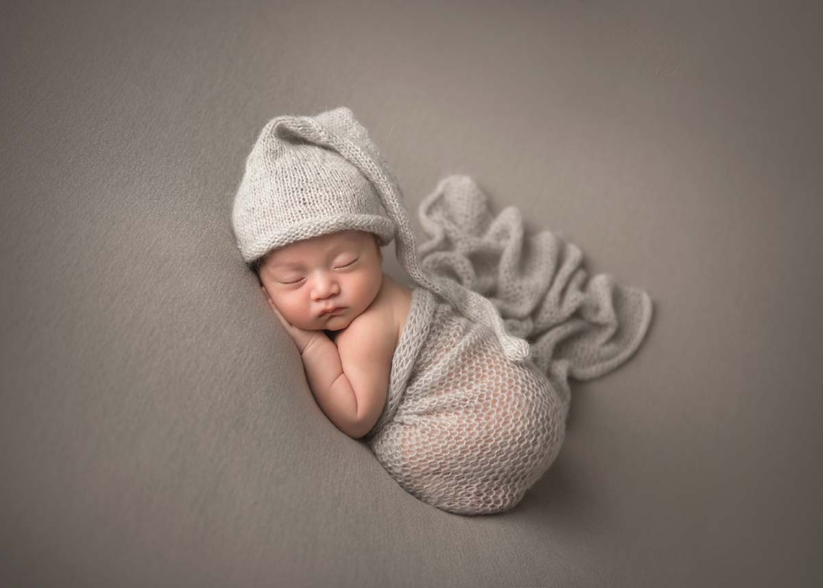 Professional newborn photographer captured this beautiful photo of a Denver Colorado baby wearing a gray knit hat