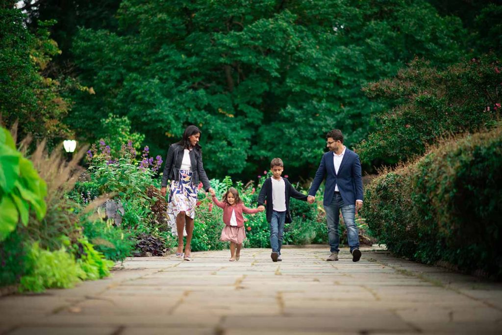 Family with children holding hands and walking in a botanical garden in Rye, NY