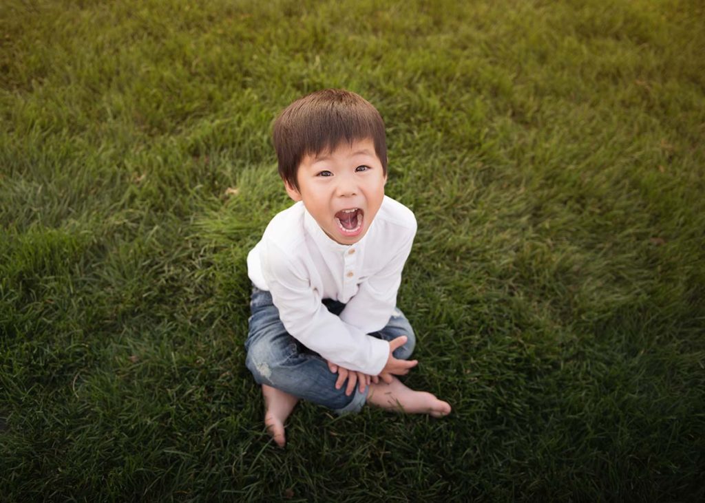 Little boy in a white shirt and jeans laughing happily in this baby photo