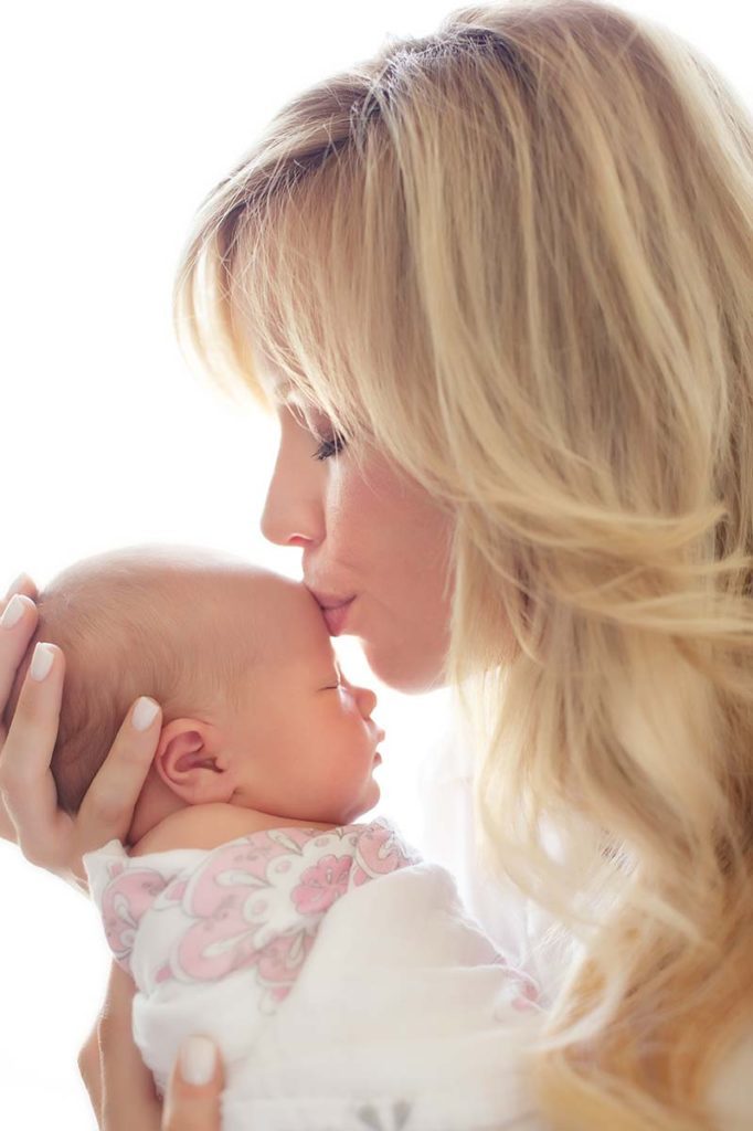 Attractive blonde woman kissing her baby in this photograph taken in Westchester County, NY.