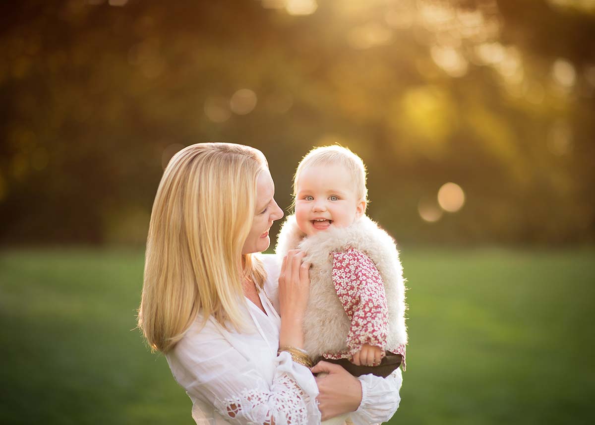 Blonde woman holding a beautiful baby at sunset