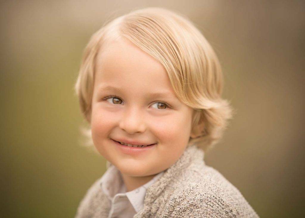 Beautiful young boy with long blonde hair smiling for the baby photographer in Connecticut