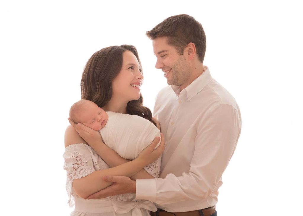 New parents embrace their newborn baby as documented by a newborn photographer from Greenwich, CT.