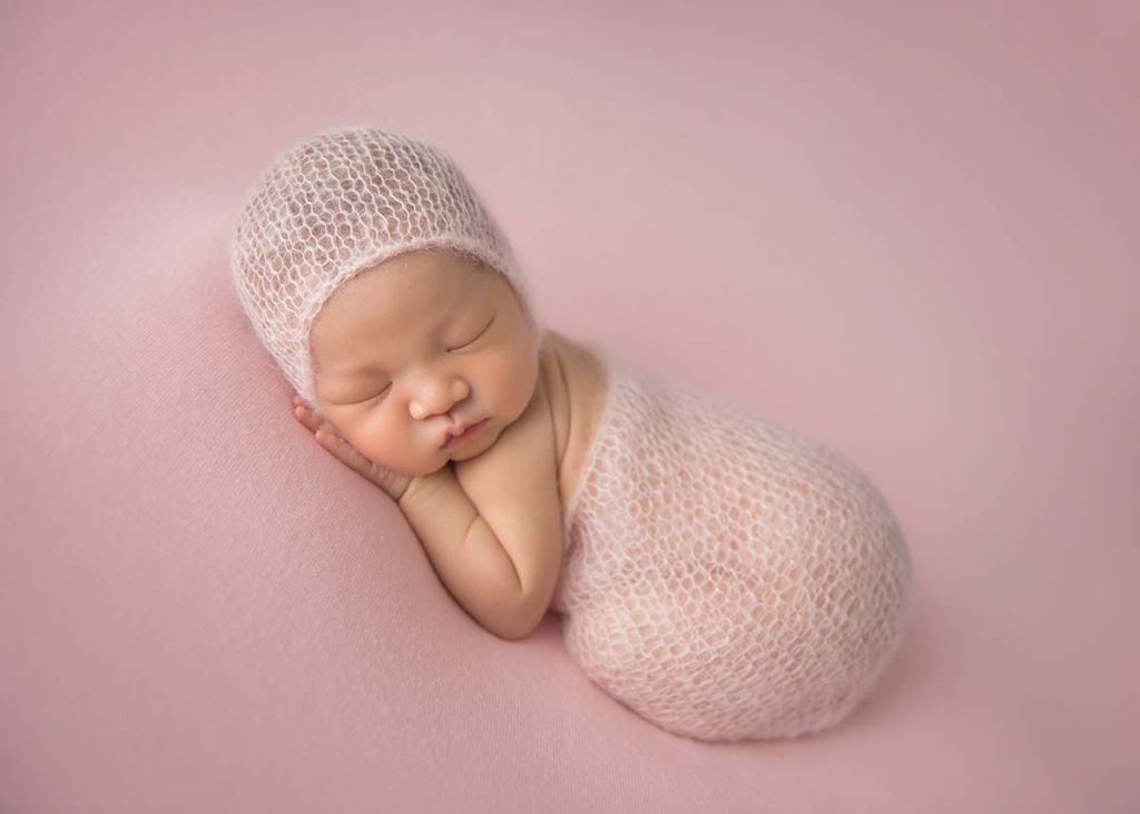 Pink blanket makes the perfect bed for this sleepy newborn baby