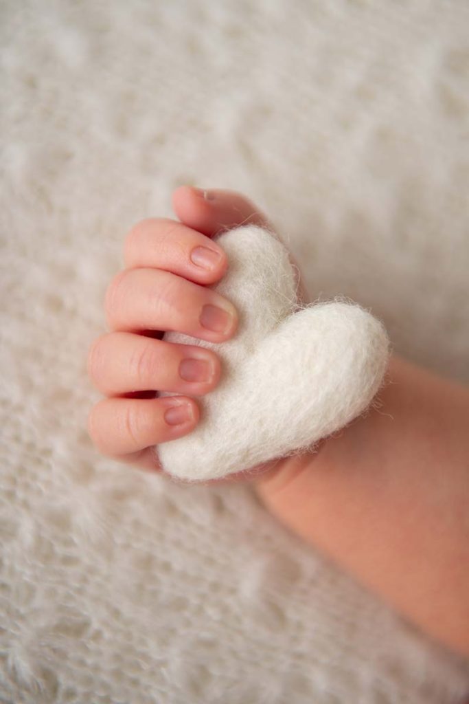 Newborn baby holding a felt heart in his hand in this adorable photo