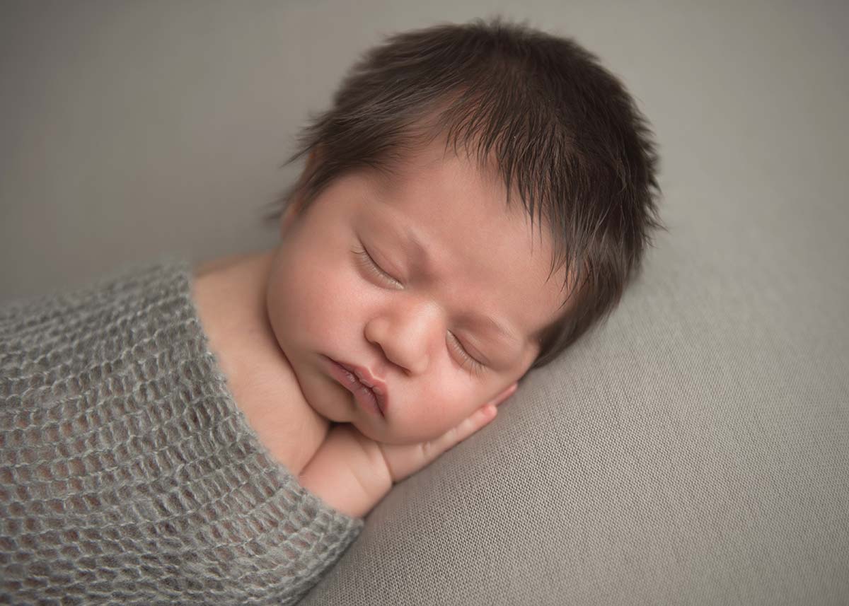 Newborn baby with thick black hair sleeping peacefully in this photograph taken in Denver