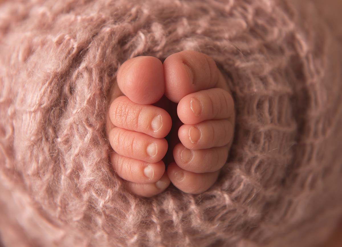 Close up image of baby's toes as wrapped in a knit swaddle
