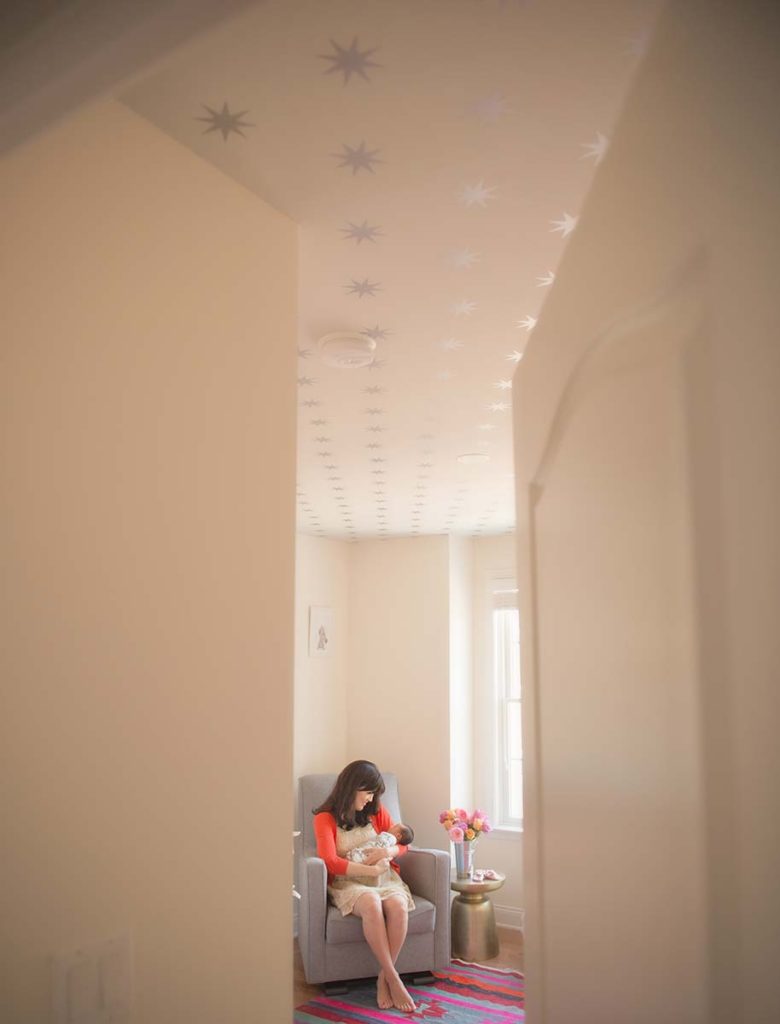 Twinkle stars line the ceiling of this Stamford CT nursery where a mother enjoys a bonding moment with her newborn baby.