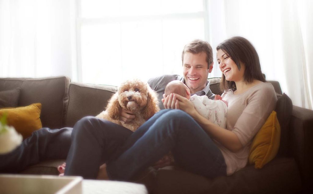 parents holding baby dog A happy moment with a family smiling at their newborn baby in their living room