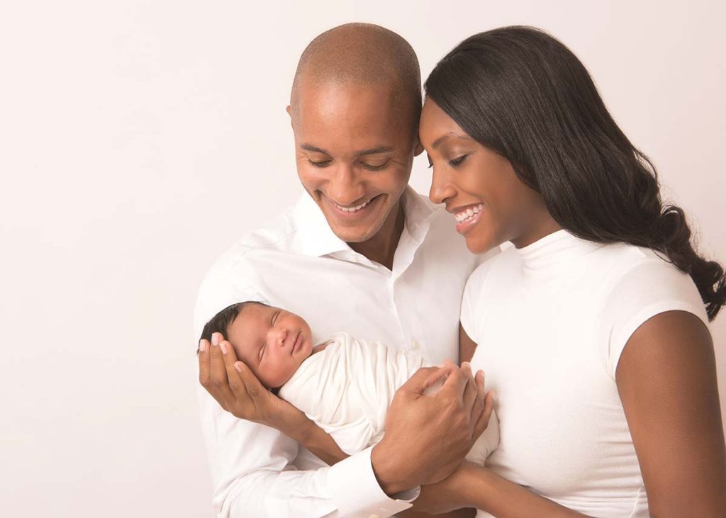 Joyous mother and father holding their beautiful newborn baby in this photo