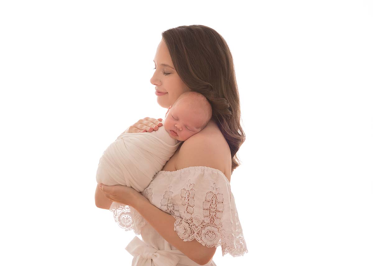 Mother holding her baby boy on her shoulder in this captivating newborn photo