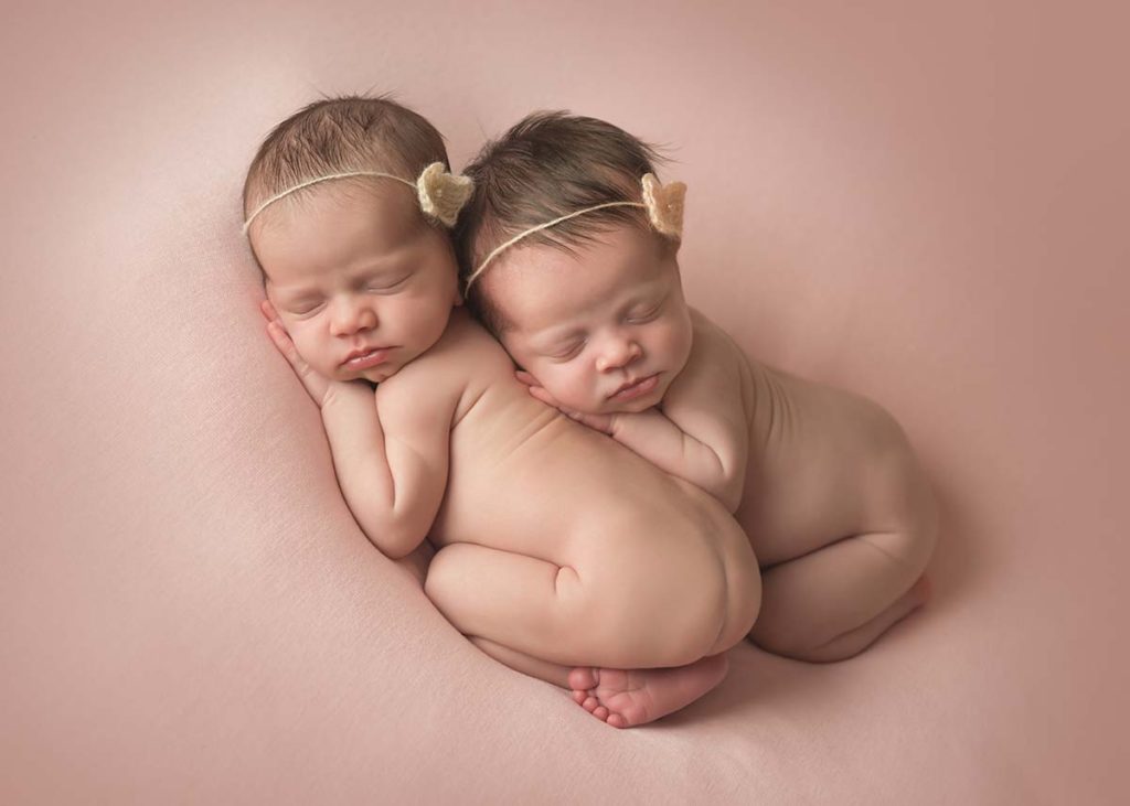 Two twin babies sleeping together in this priceless newborn photo