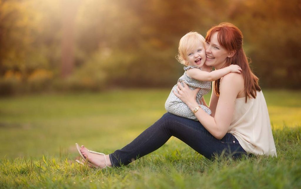 redhead mother hugging baby girl Mother with red hair kissing her beautiful daughter in a park