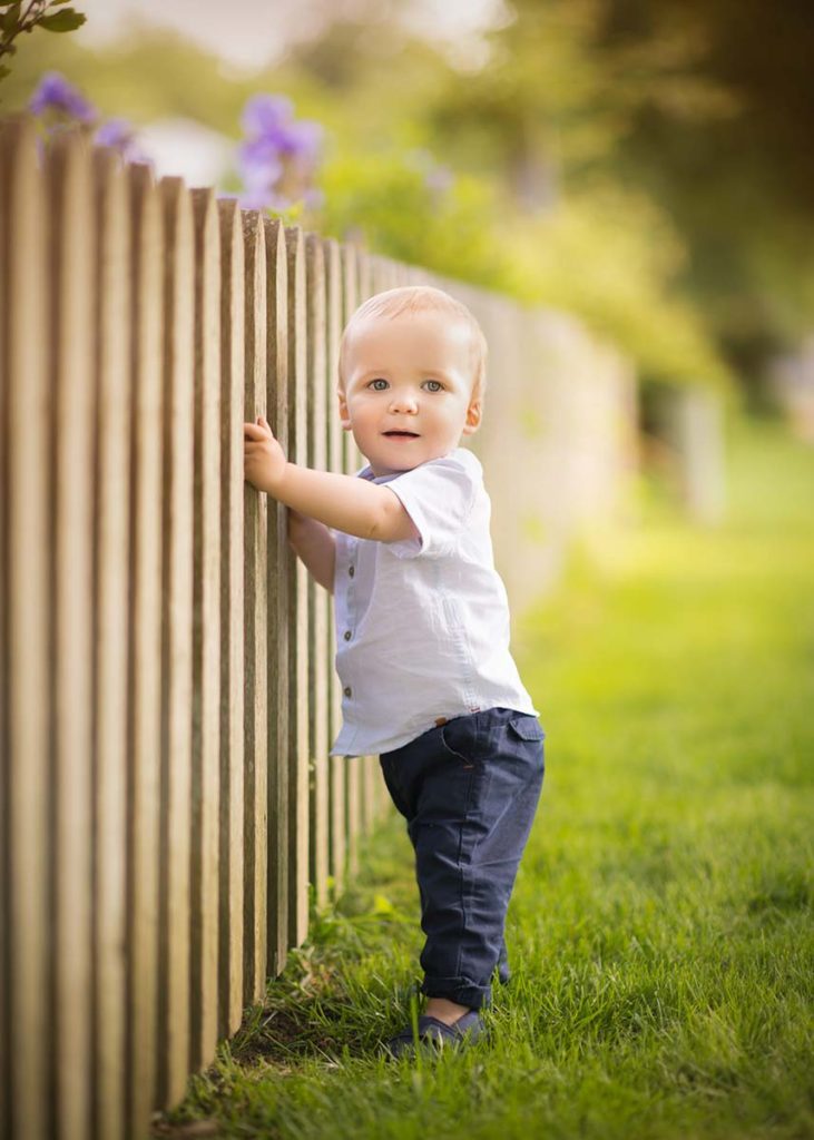 Wooden picket fence held by a toddler boy