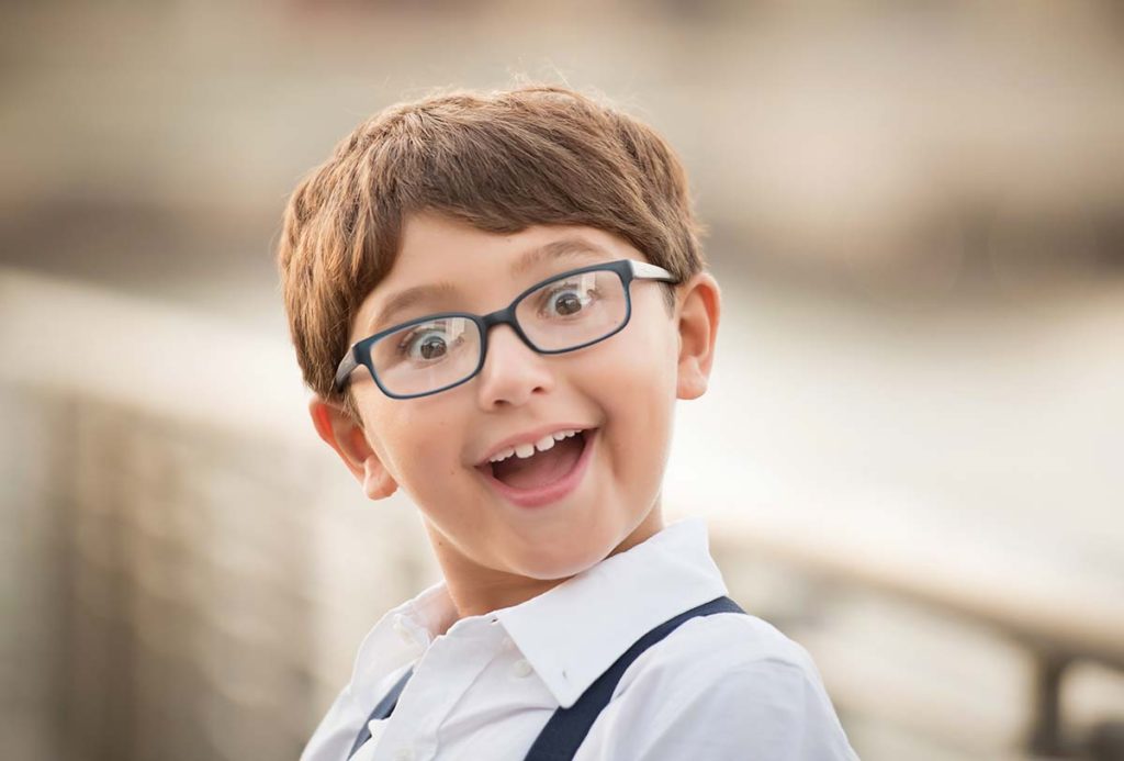 Young boy in glasses making silly faces at the camera in this beautiful child photo