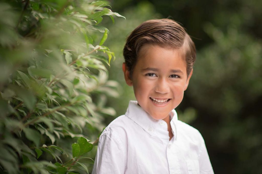 Botanical Gardens in Westchester Co, NY are the setting for this beautiful photo of a young boy in a white shirt smiling for the camera