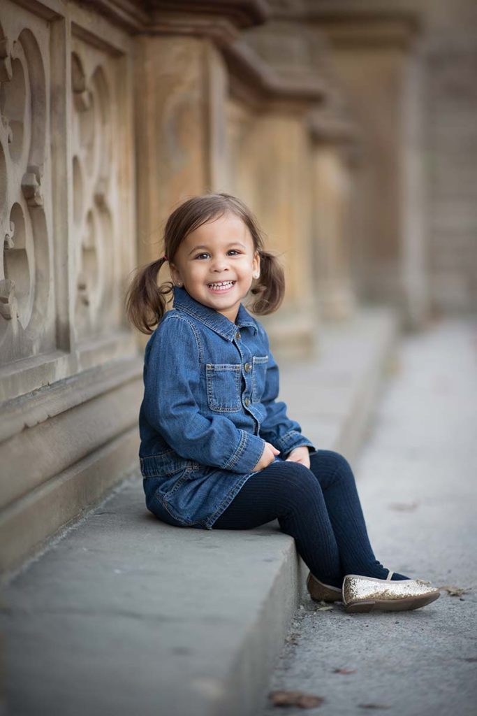 Cute baby girl sitting on a bench at a park and smiling