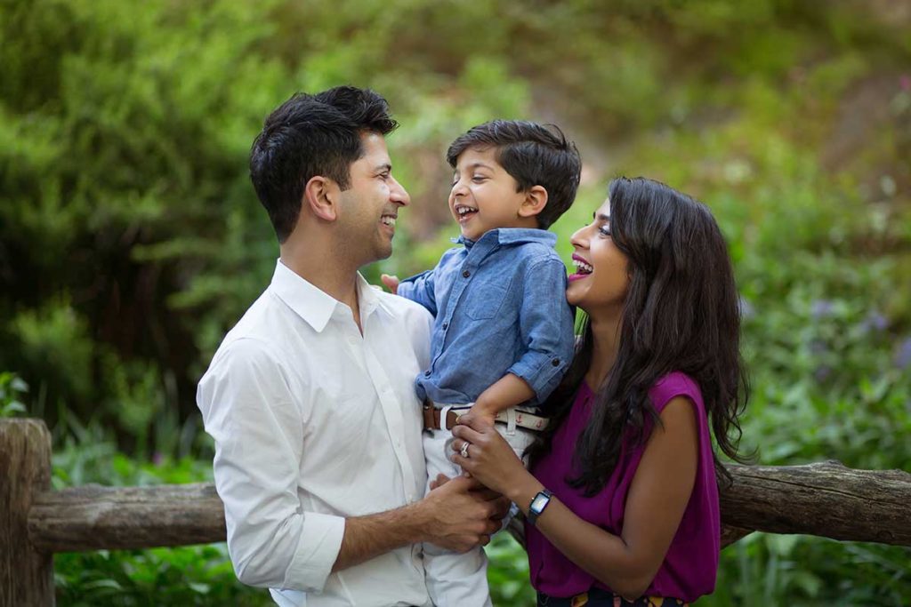 smiling parents holding baby Beautiful family photo of parents smiling at their child in a park setting in Connecticut