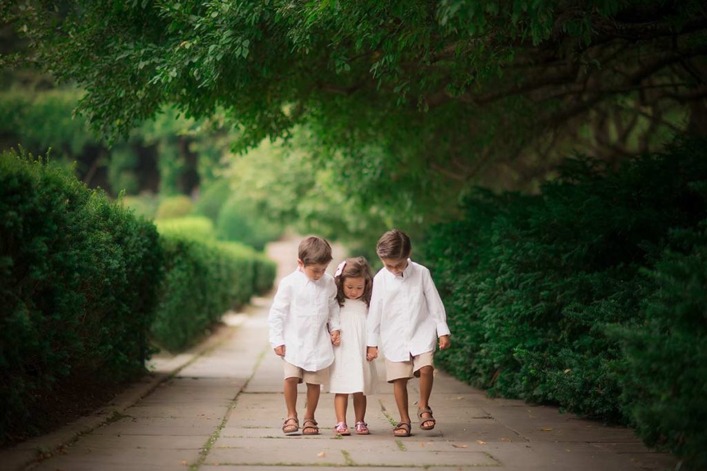 Three children walking on a paved path in botanical gardens near Scarsdale, NY