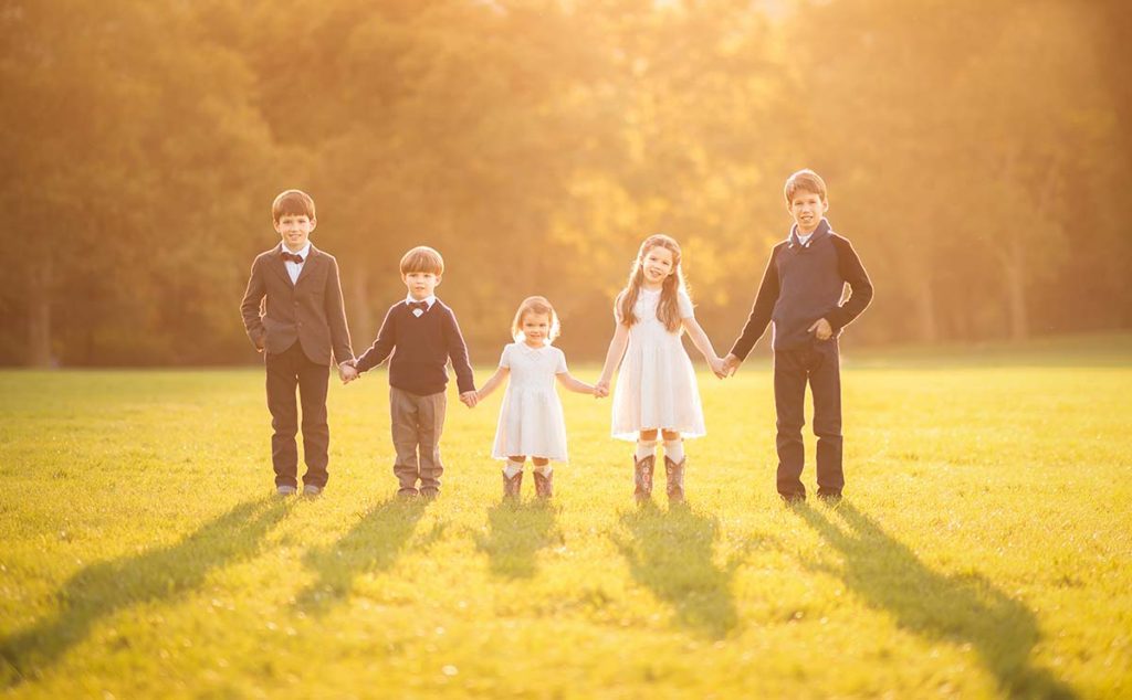 sunset children standing together outdoors Five little children holding hands during a sunset at a beautiful setting at a park in Westchester County, New York.
