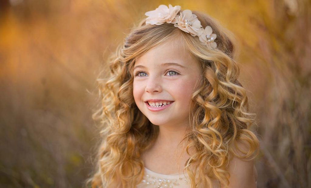 Beautiful young girl with curly blonde hair and a headband smiling