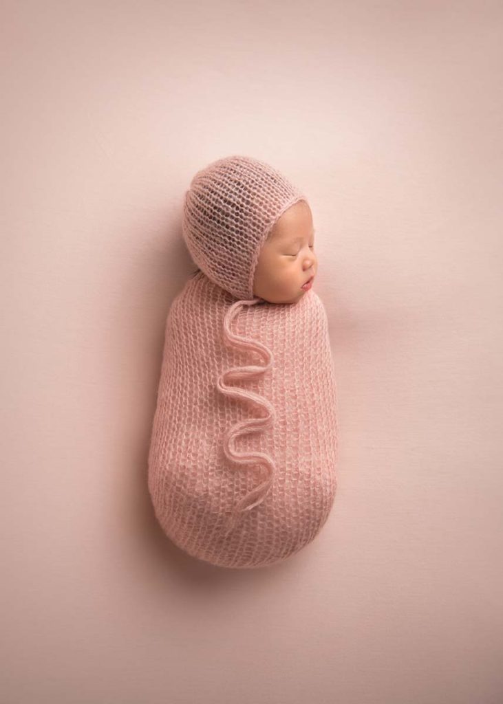Swaddled newborn baby with a beautiful hat sleeping in this photo