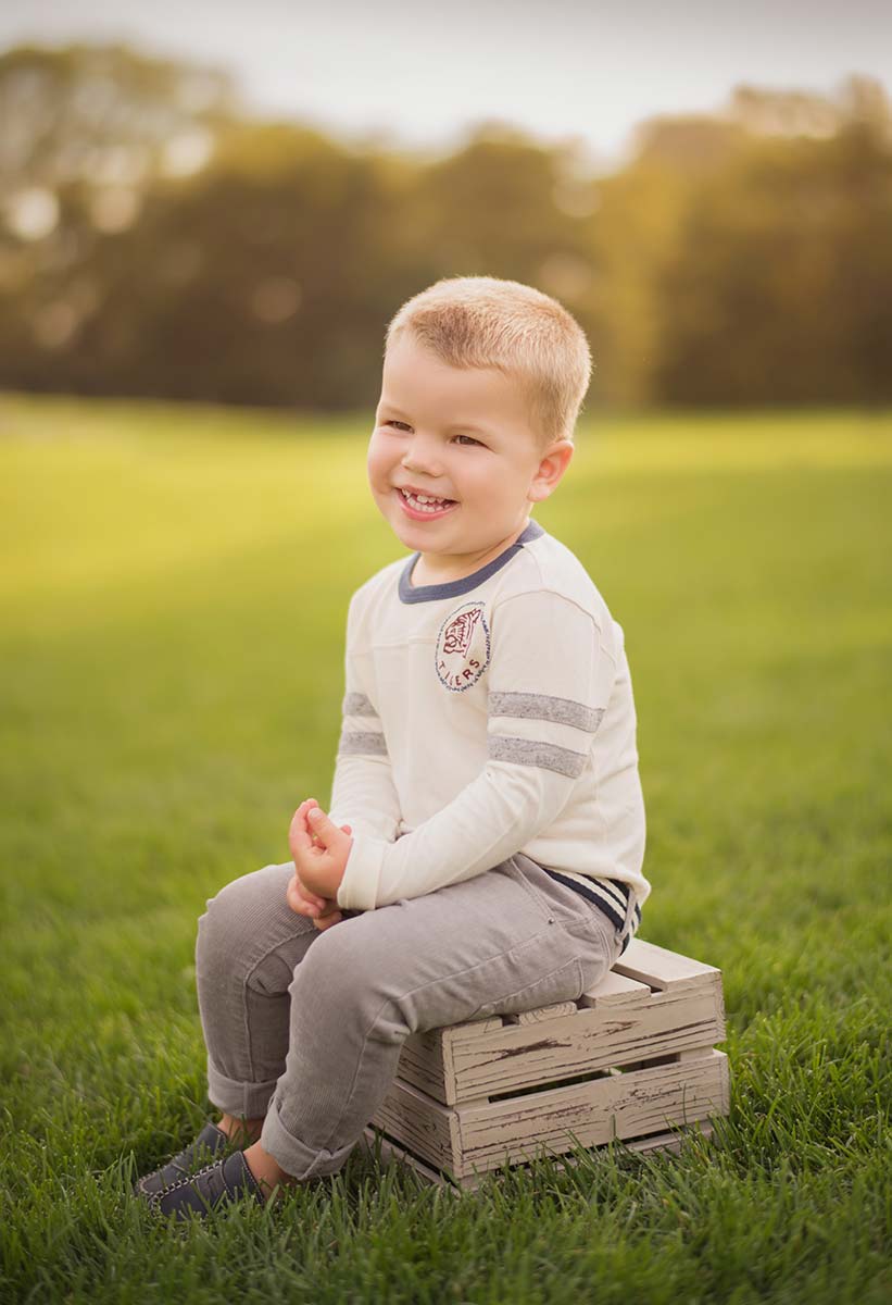 Handsome child sitting on a wooden crate at a park near Denver, CO.