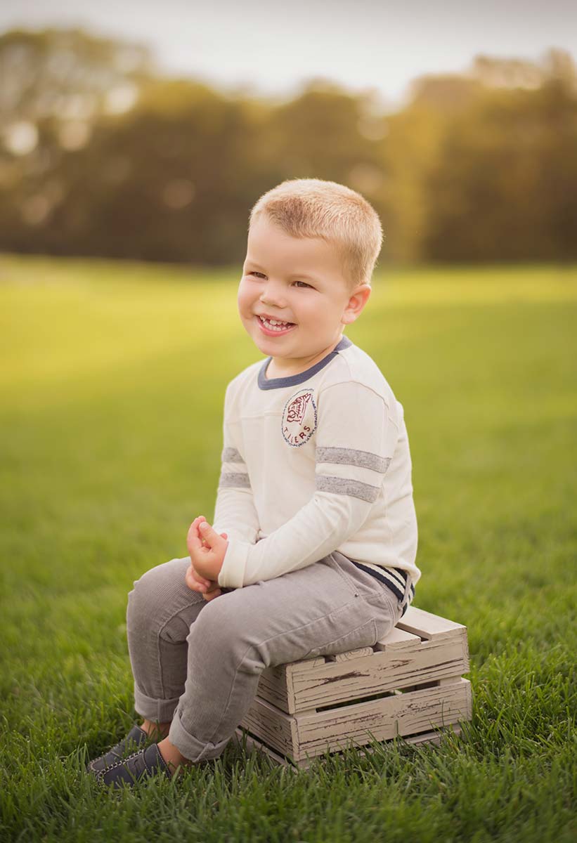 Handsome child sitting on a wooden crate at a park near Greenwich Connecticut.