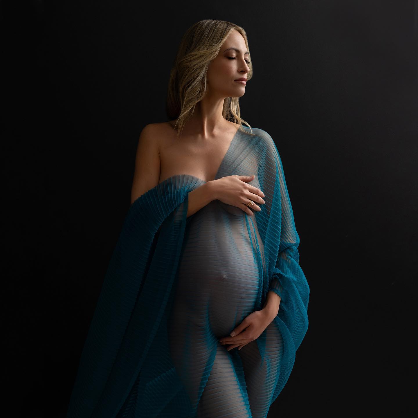 Pregnant woman posing in black background. 
