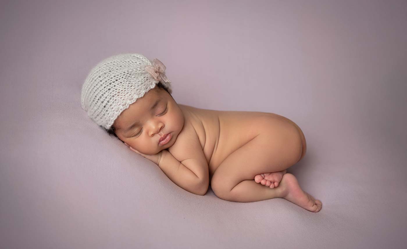 A sleepy newborn baby on a pink blanket in Denver